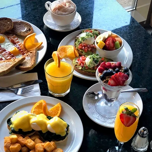 Symposium Cafe Restaurant all-day breakfast menu featuring Eggs Benedict, omelettes, waffles and specialty coffee.